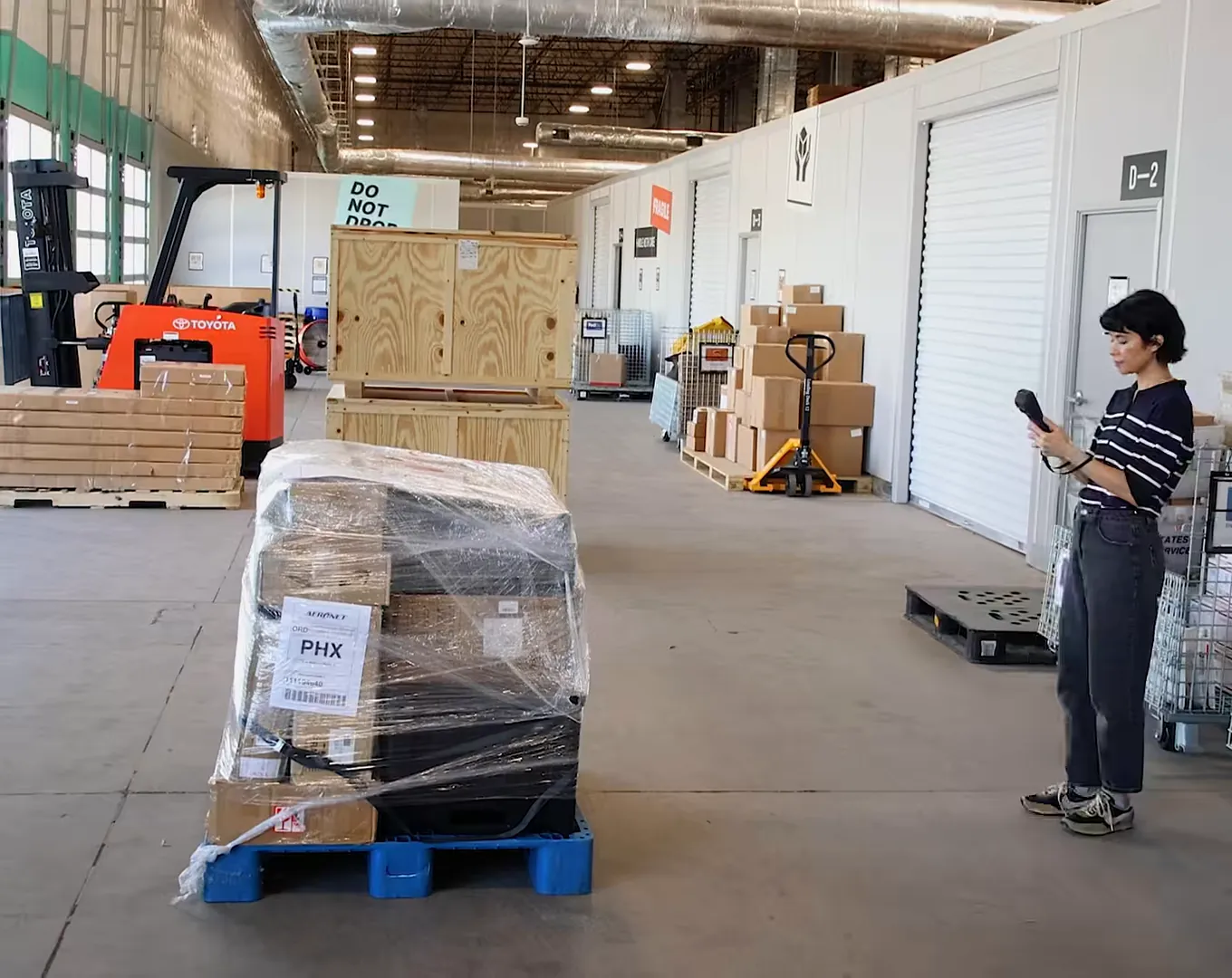 An operator holds the M2 beside a shrink-wrapped pallet on the warehouse floor